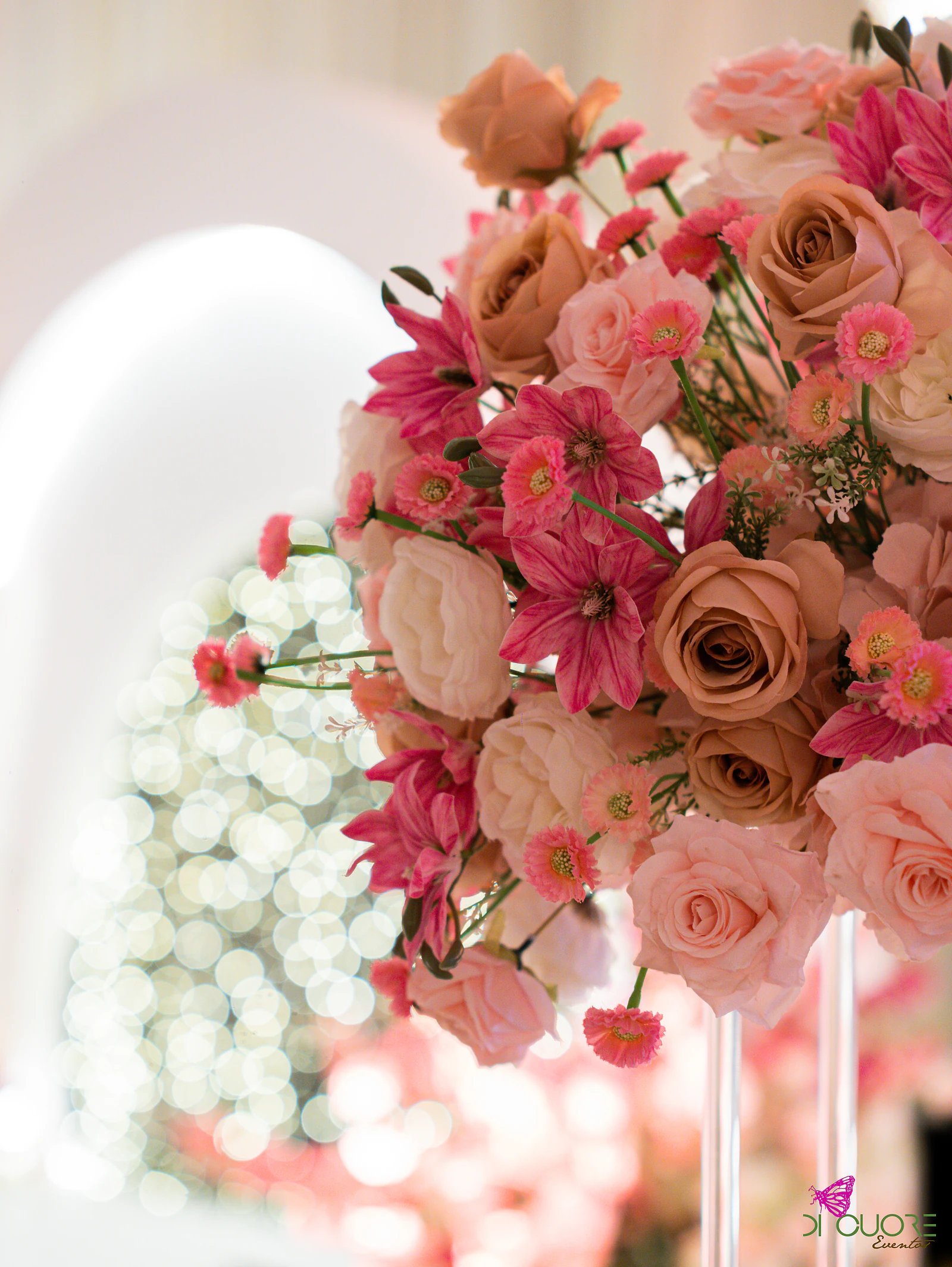 Rosas cor de caramelo e cor-de-rosa com pequenas gerberas, com luzes desfocadas ao fundo