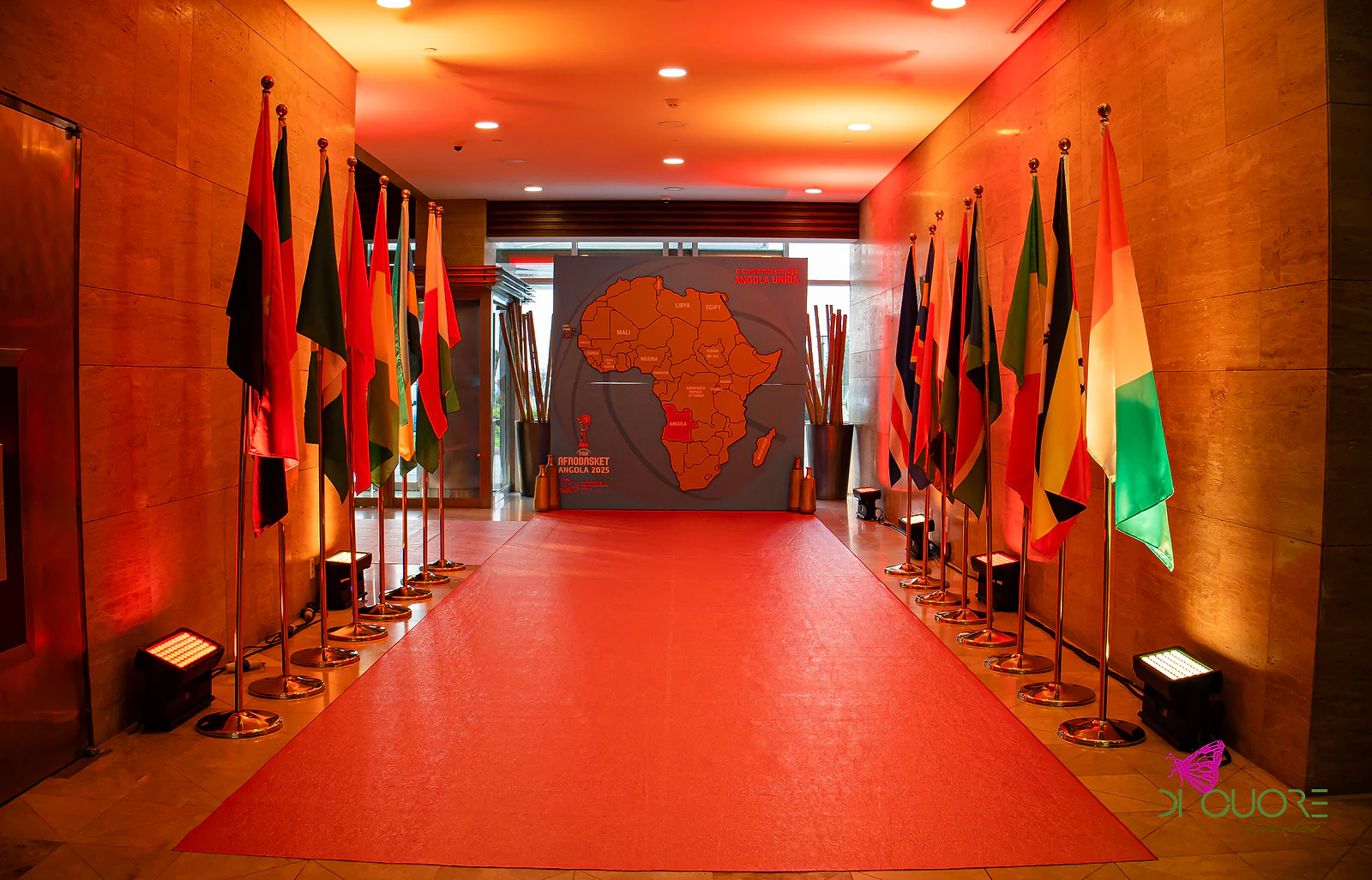 Corredor com passadeira vermelha, mastros de bandeiras africanas e um painel com o mapa de África ao fundo