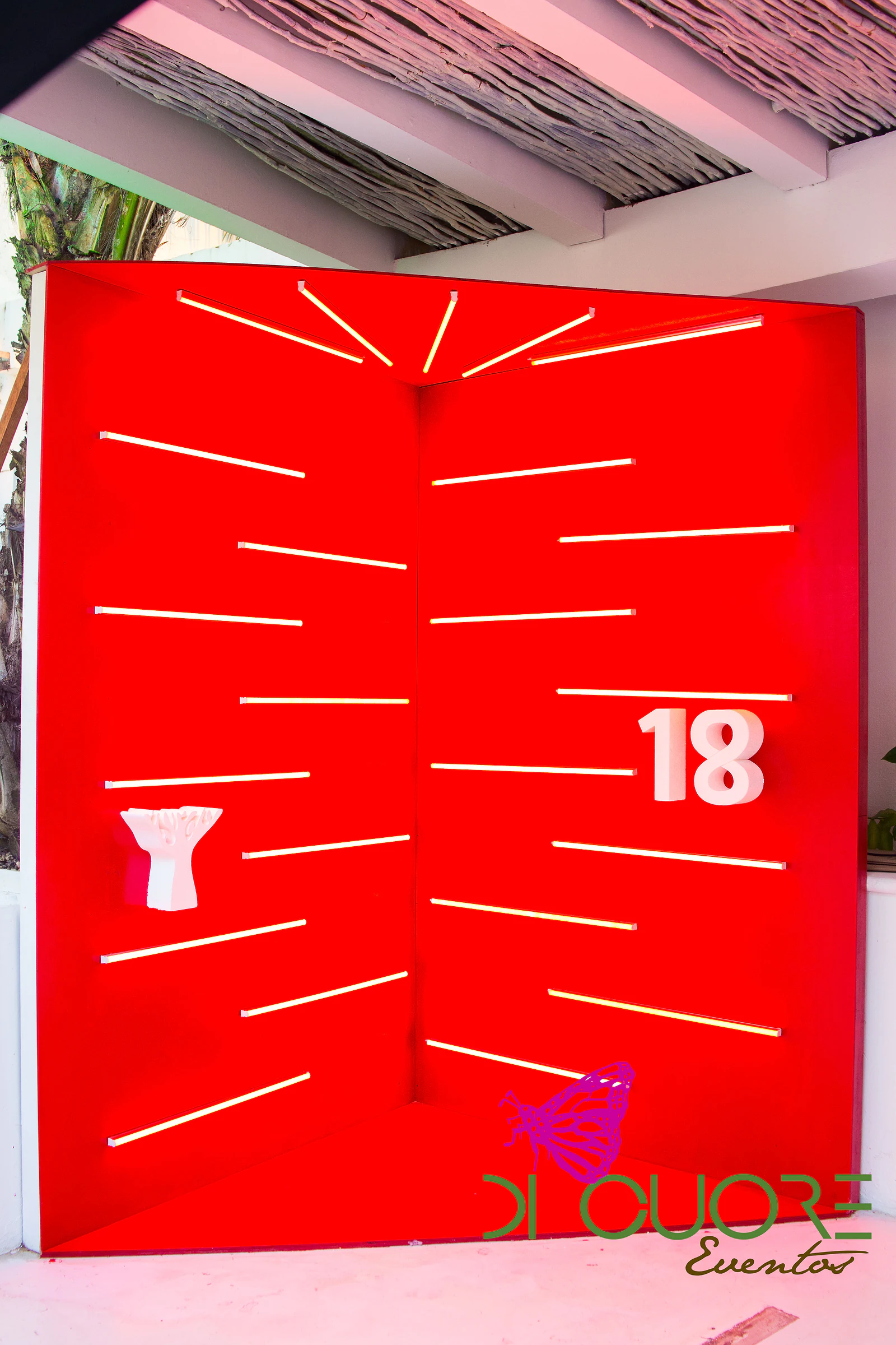 Red panel with white strips of light and a raised number 18, beneath a slatted ceiling