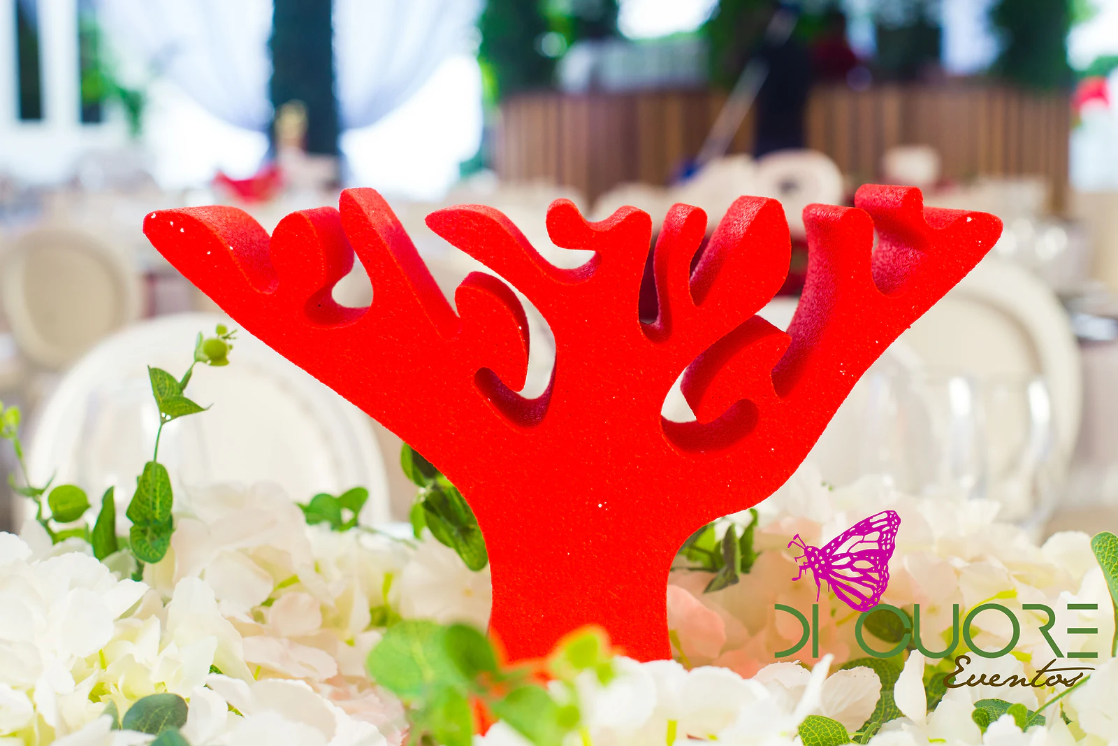 Red coral-branch ornament above a centrepiece of white hydrangeas and green leaves