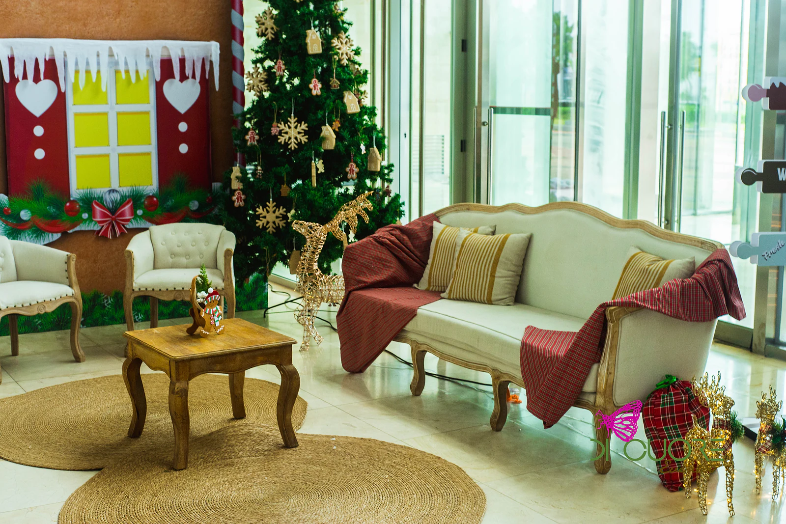 Canto de estar com sofá creme e mantas axadrezadas, poltronas, mesa de madeira sobre tapetes de corda e árvore de Natal