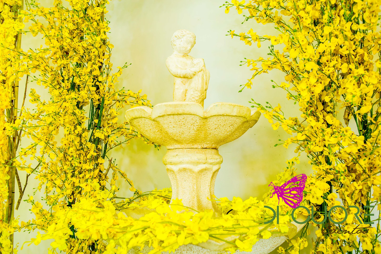 Fonte de pedra com um menino esculpido, emoldurada por ramos de flores amarelas