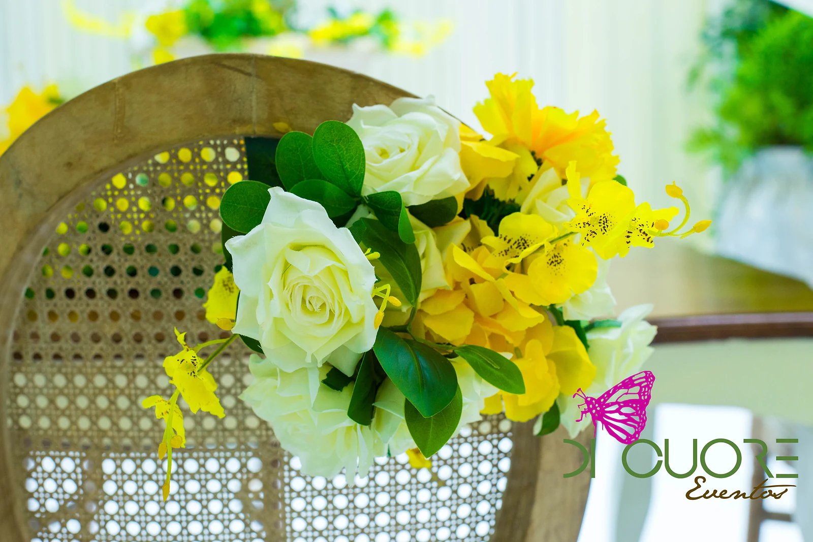 Cane back of a wooden chair with a small posy of white roses, yellow flowers and leaves