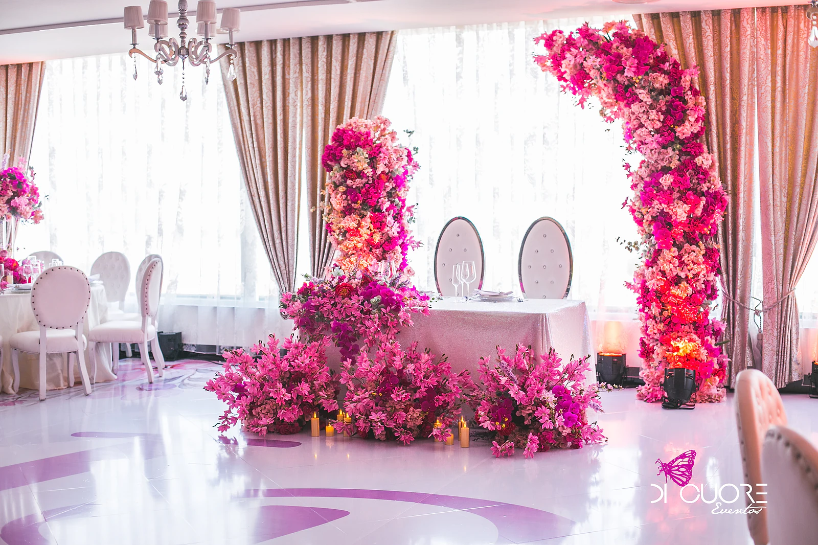 Top table with arches of pink and magenta flowers in a hotel ballroom