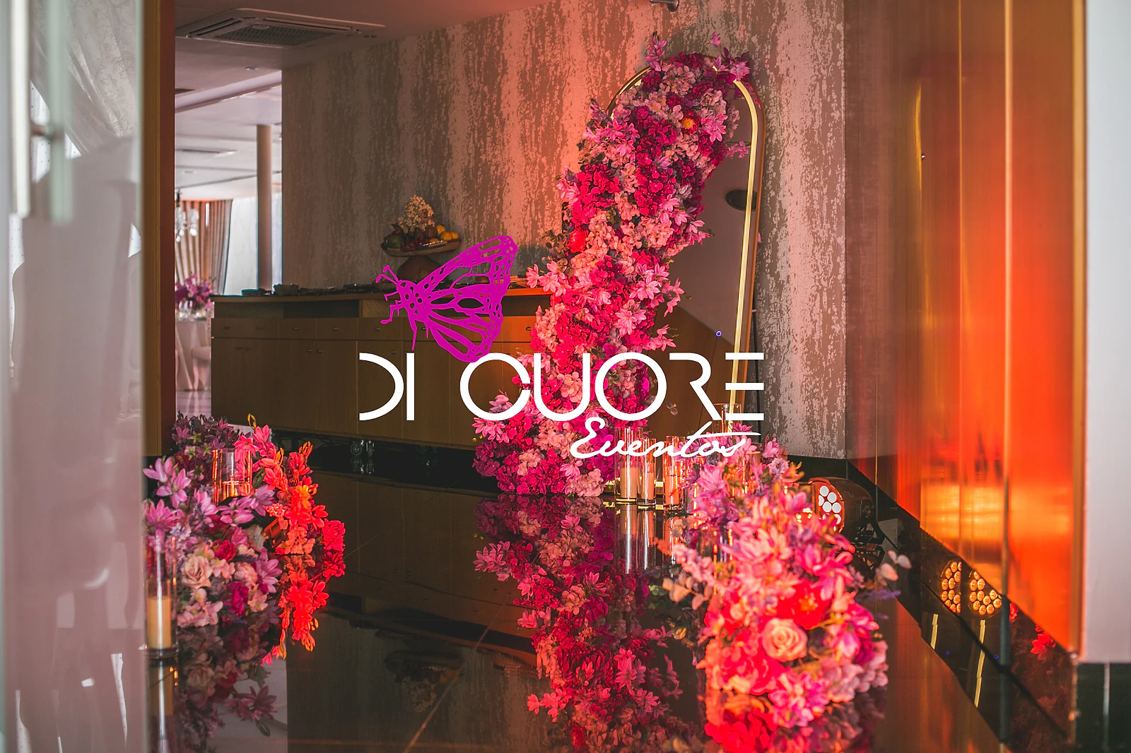 Staircase decorated with red and pink flowers and the illuminated Di Cuore logo