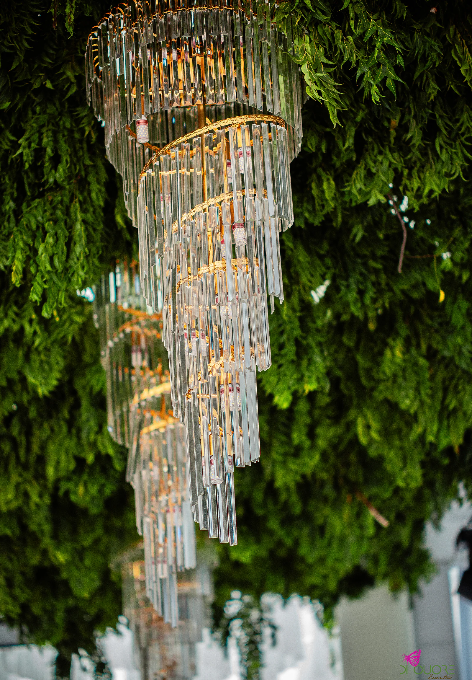 Lustre de cristal em espiral pendurado numa cobertura de folhagem