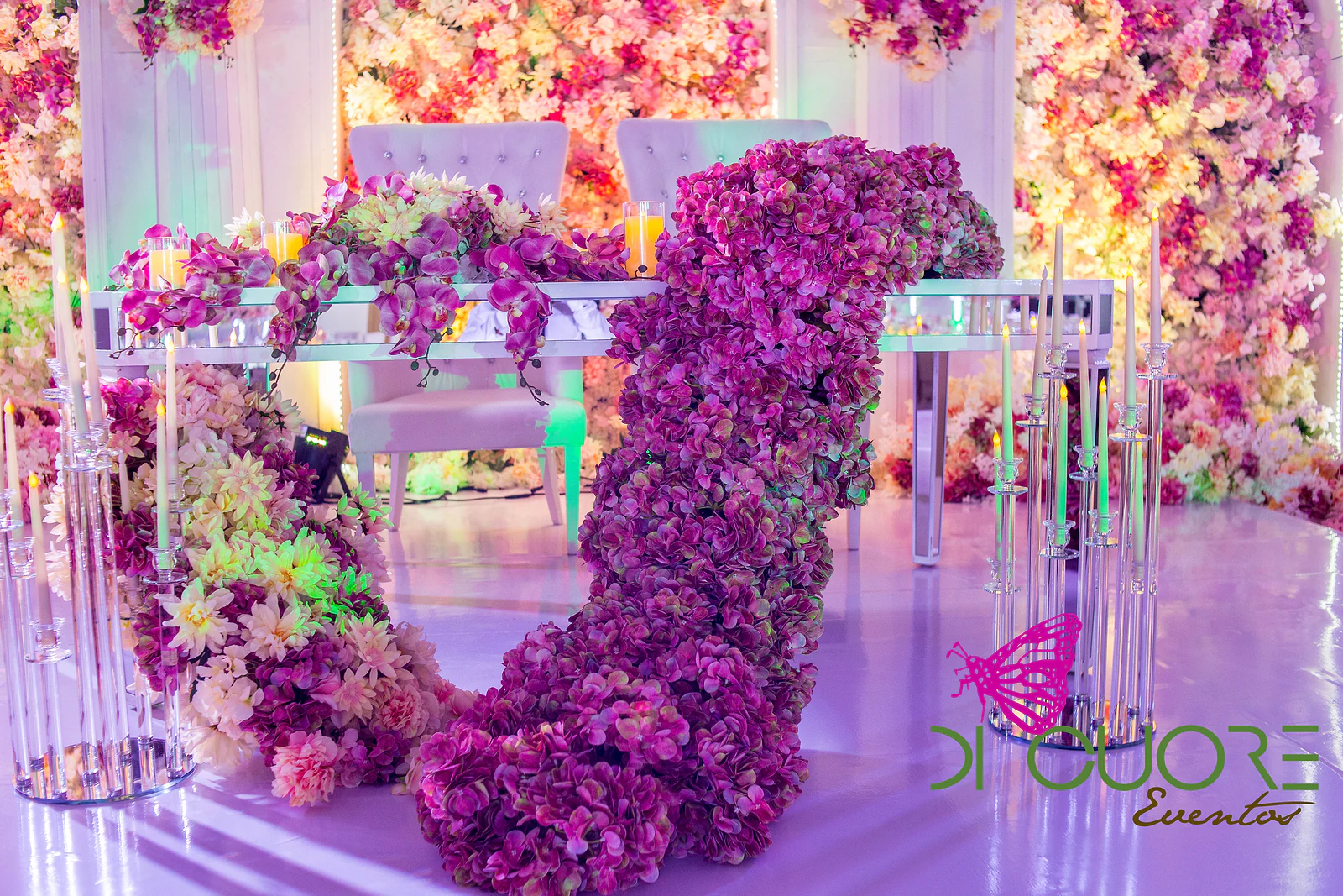 Cascade of purple flowers falling from the main table, between crystal candelabra and a wall of flowers behind.