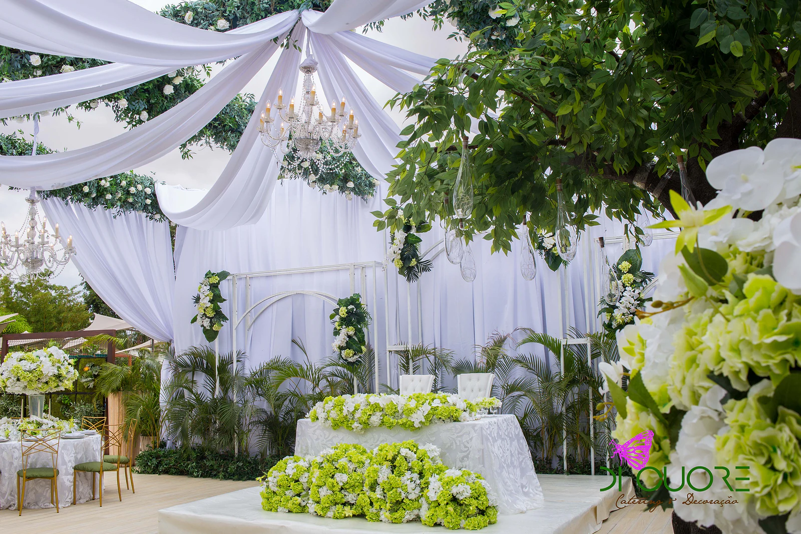 Main table with a band of lime-green and white hydrangeas, seen past white orchids in the foreground and a tree on the right