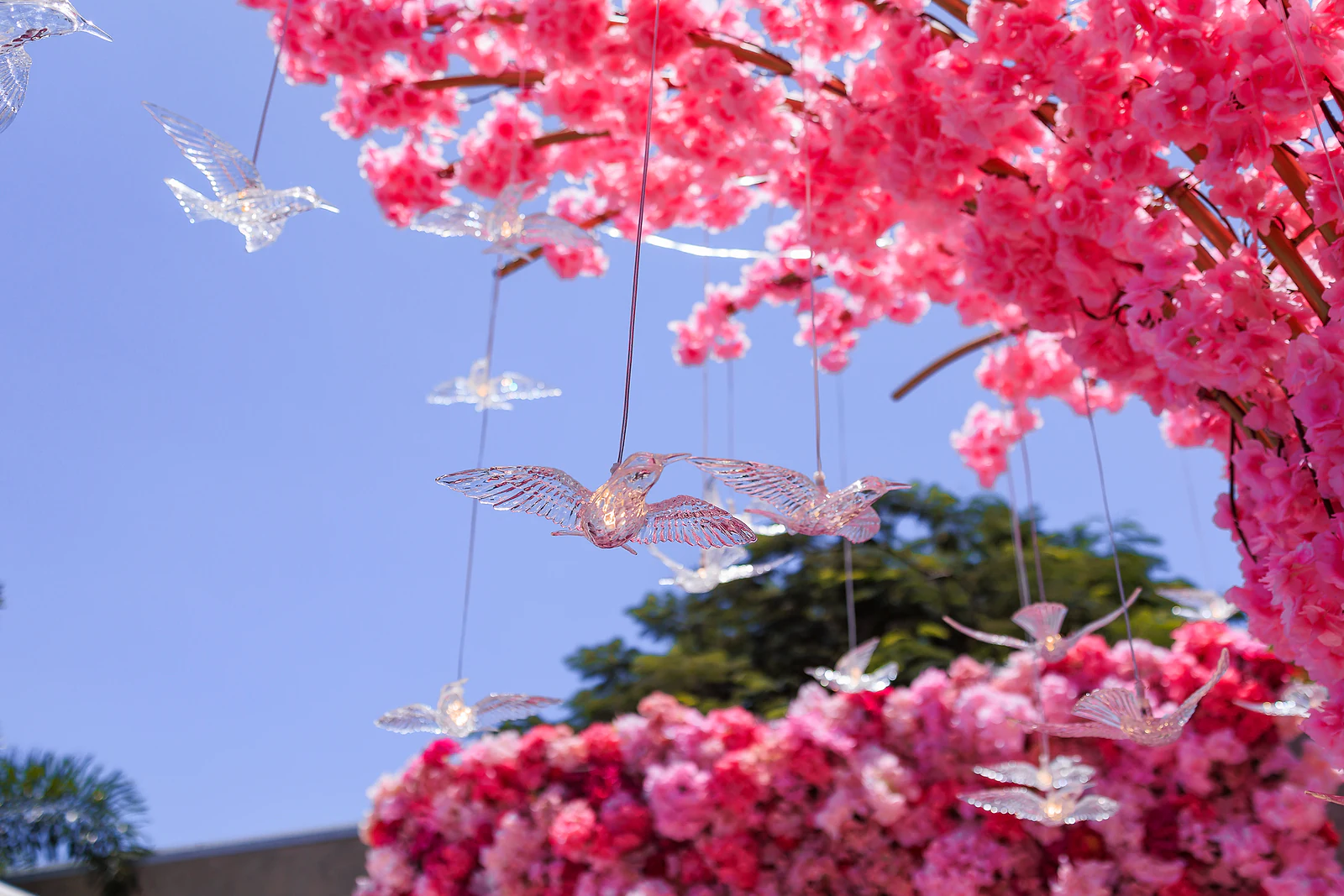 Pormenor de borboletas de cristal entre ramos de flores cor-de-rosa
