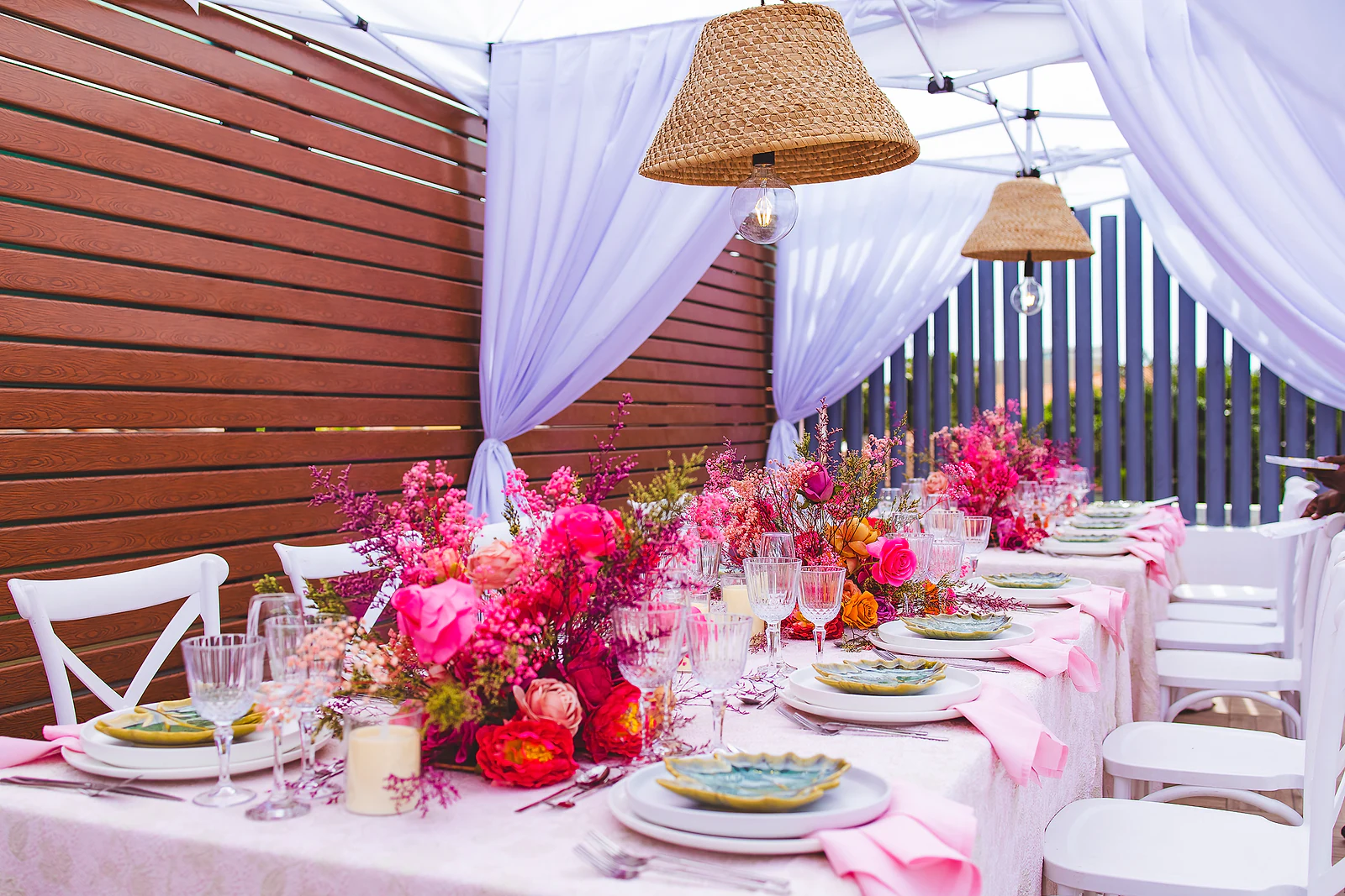 Long table under a white voile marquee with straw lamps