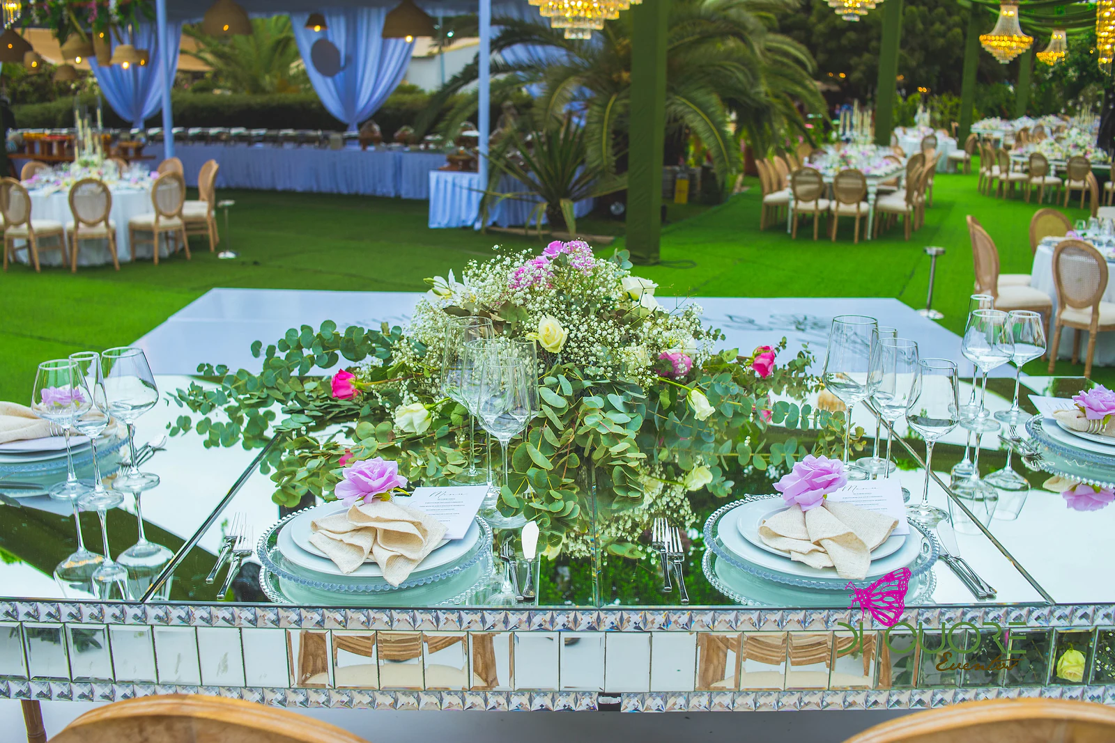 Mesa de espelho com um ramo baixo de rosas e folhagem, pratos azul-pálido e guardanapos com rosa lilás