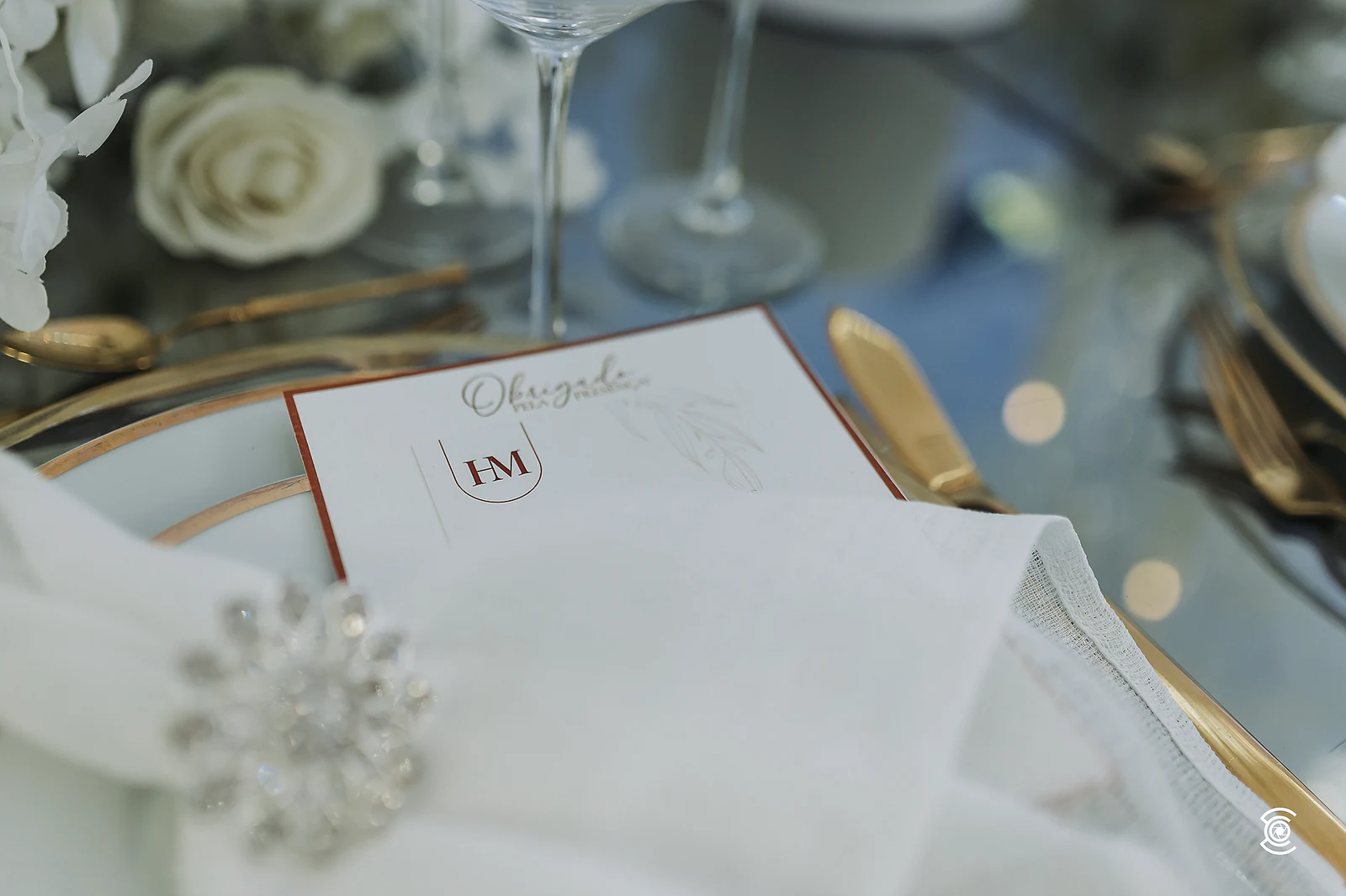 Menu with the HM monogram on the plate and a napkin with a brooch