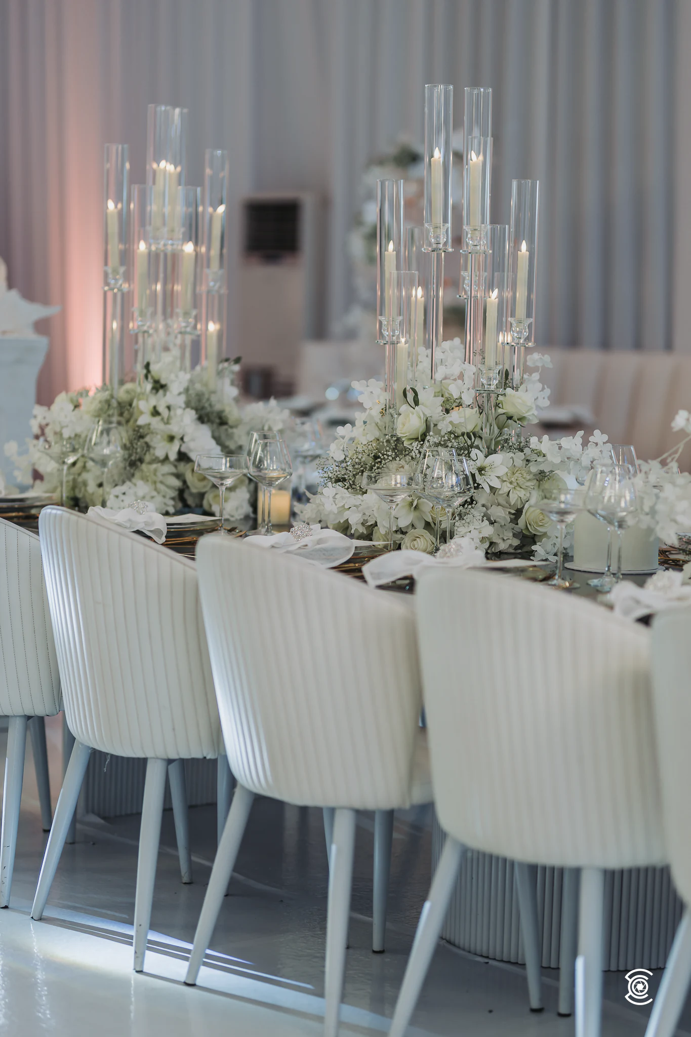 Upholstered white chairs lined up along the guest table
