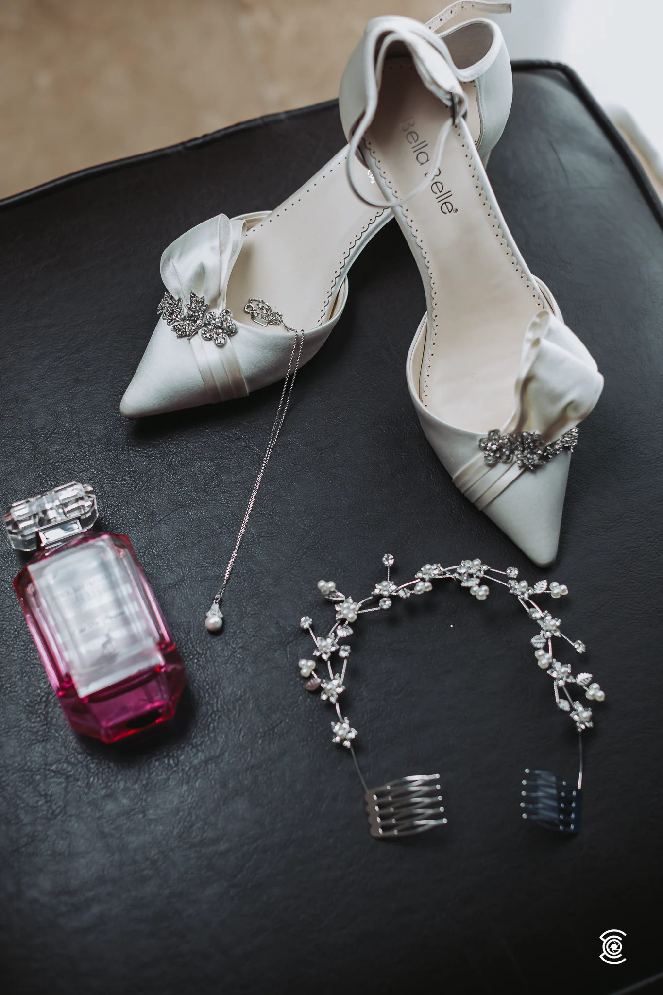 Sapatos de noiva, perfume e tiara sobre fundo escuro