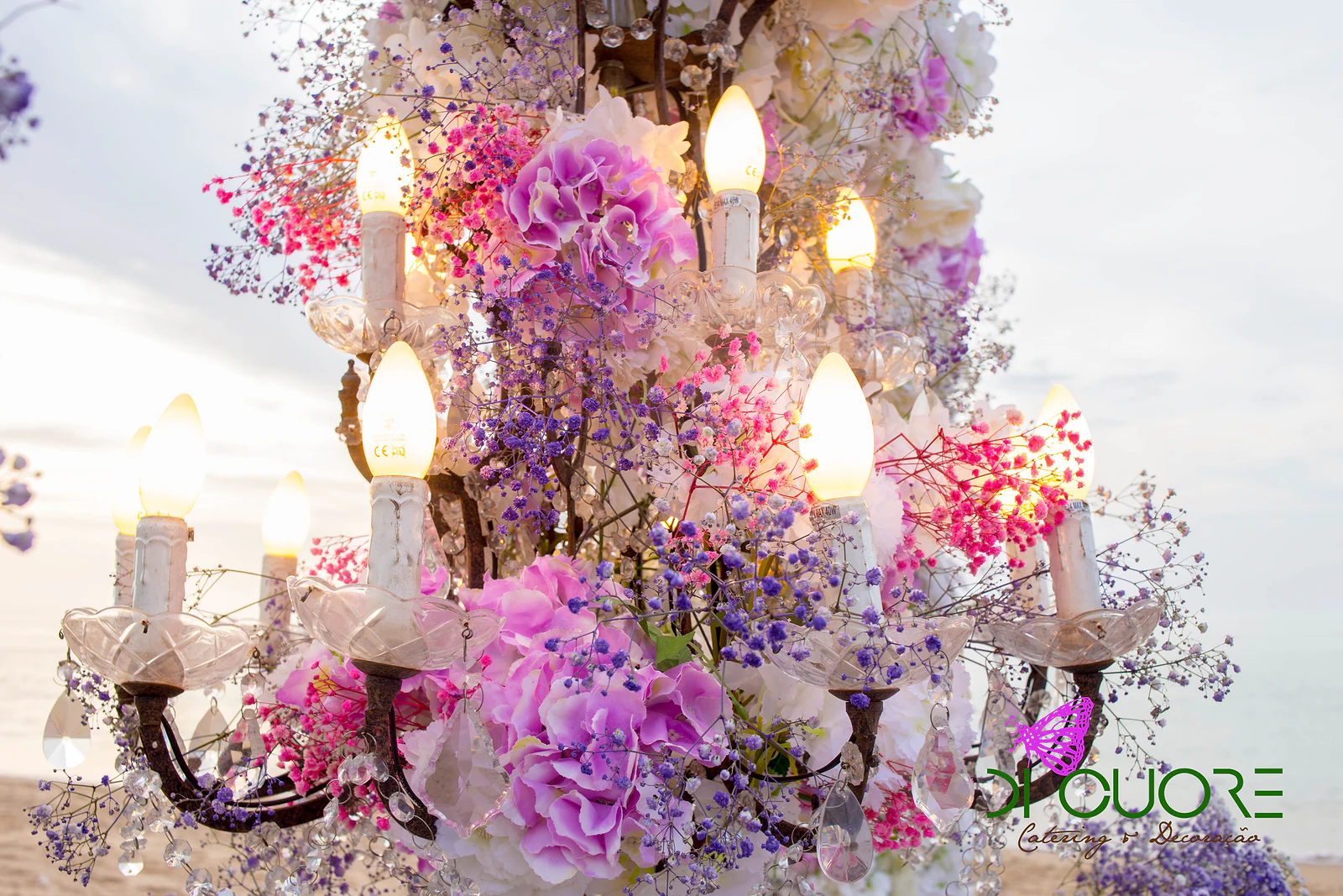 Lustre de velas coberto de hortênsias cor-de-rosa, gipsófila lilás e flores brancas