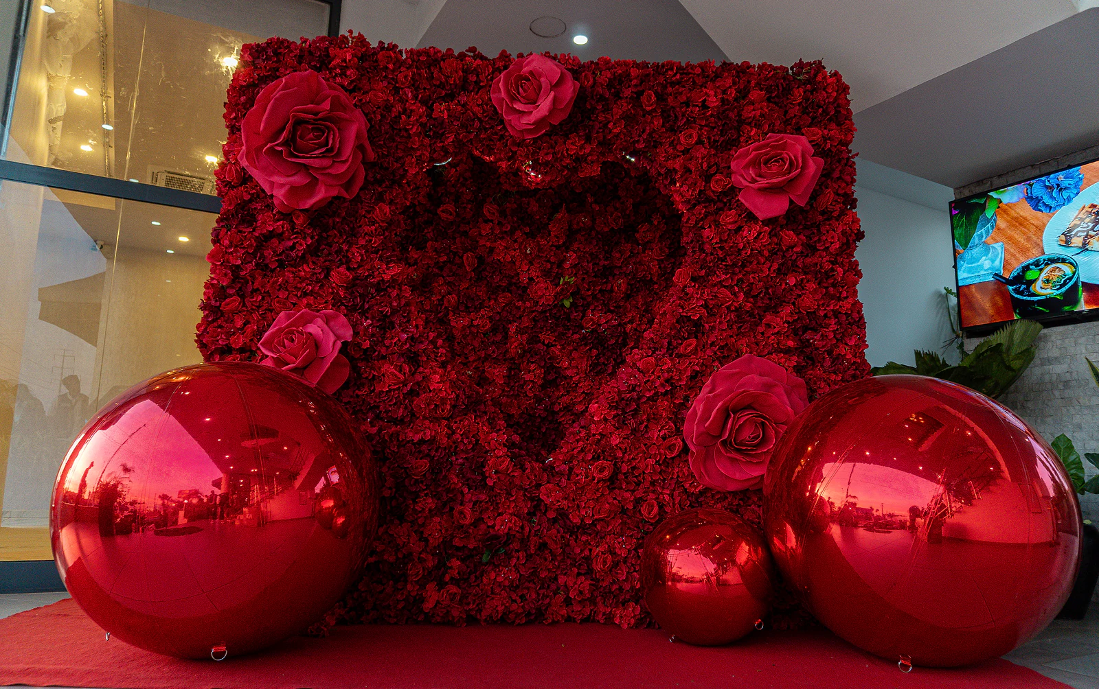 Painel de rosas vermelhas com um coração recortado e esferas espelhadas vermelhas