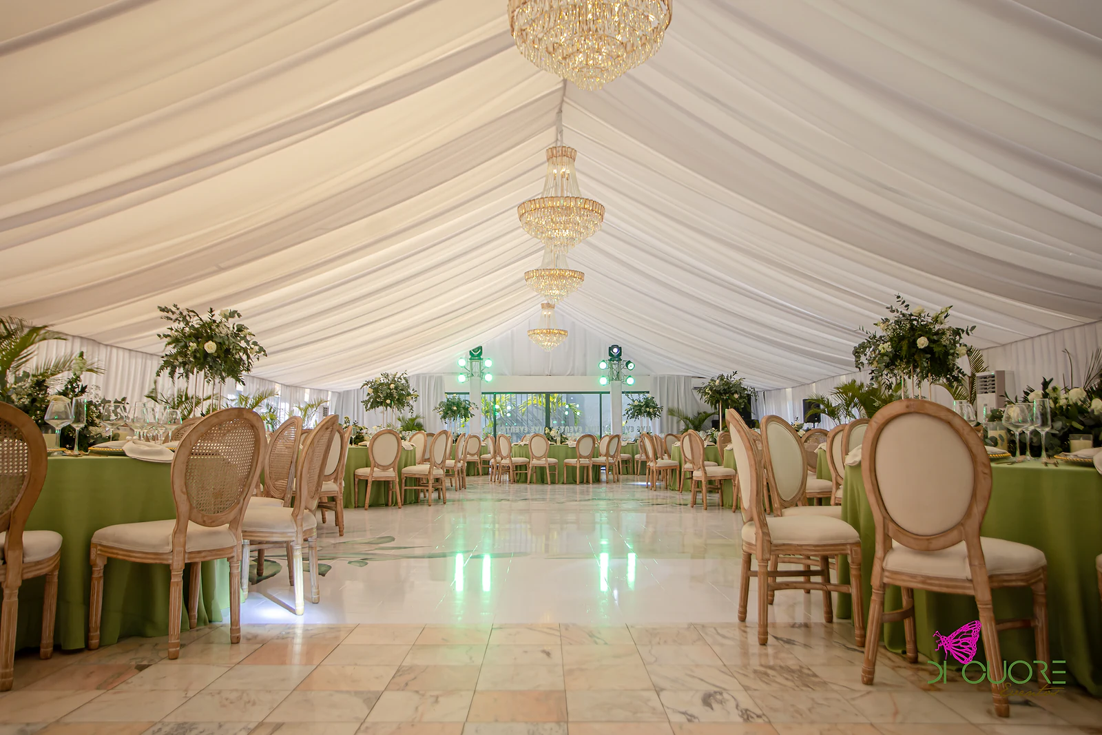 Salão com fila de candelabros de cristal sob o panejamento branco, mesas de toalha verde-pistácio e cadeiras de medalhão de cada lado