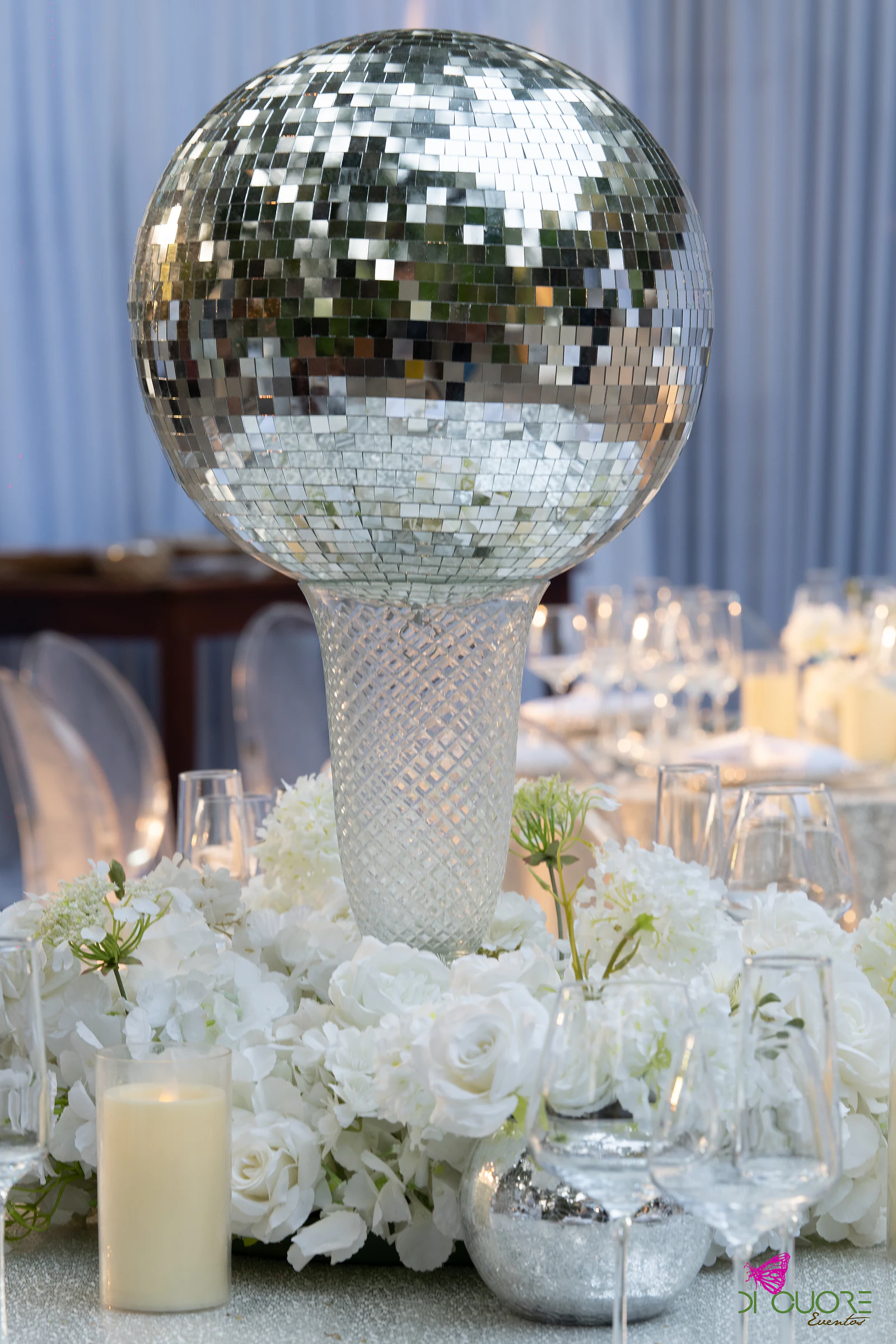 Bola de espelho sobre pedestal de cristal, rodeada de rosas brancas e velas