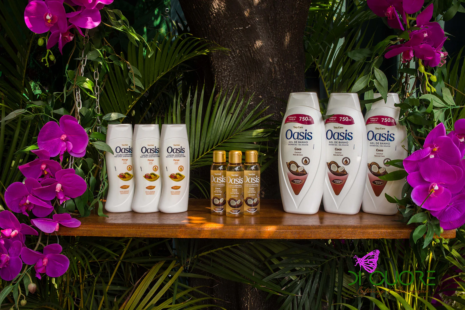 Prateleira de madeira com frascos de gel de banho e óleos Oasis, entre orquídeas fúcsia e palmeiras