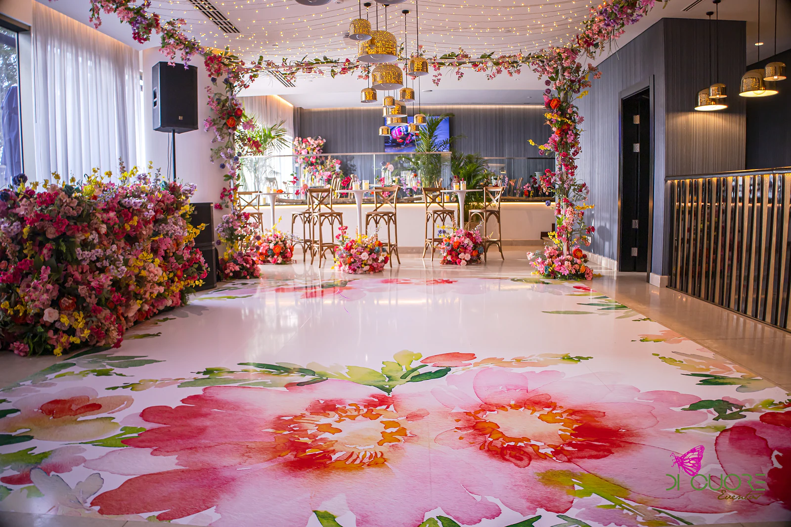 Pista branca estampada de grandes flores cor-de-rosa, com portais de flores e bancos altos ao fundo