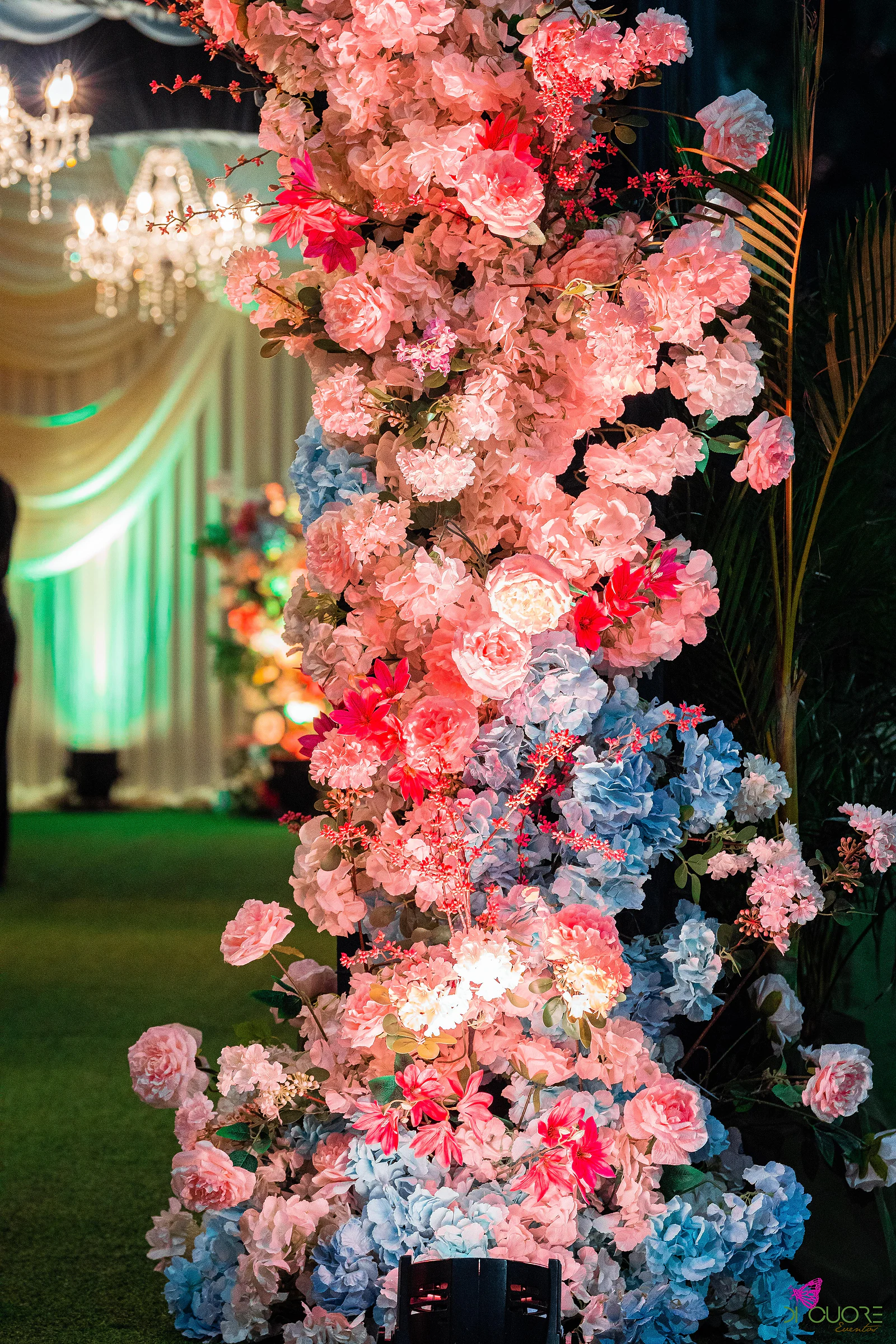 Coluna alta de rosas cor-de-rosa e hortênsias azuis, com o túnel iluminado ao fundo
