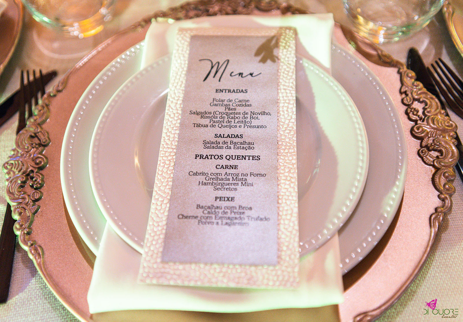 Menu impresso sobre prato branco e sousplat cobre de bordo ornamentado, com guardanapo claro
