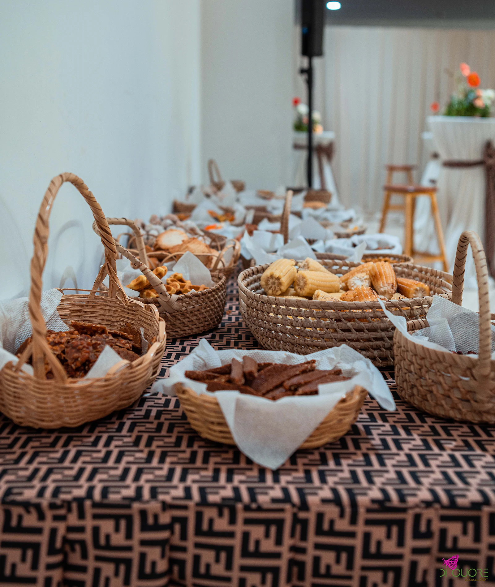 Cestos de palha com petiscos sobre uma mesa forrada a tecido castanho estampado