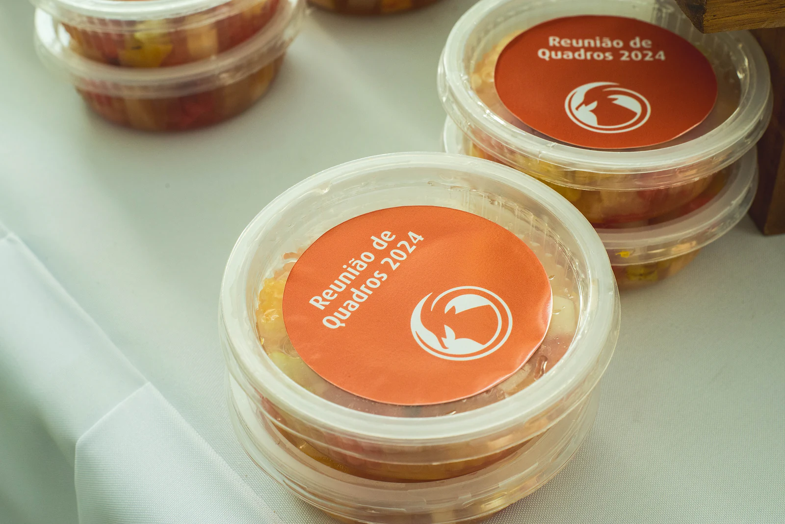 Individual pots with an orange “Reunião de Quadros 2024” label, stacked on a white cloth