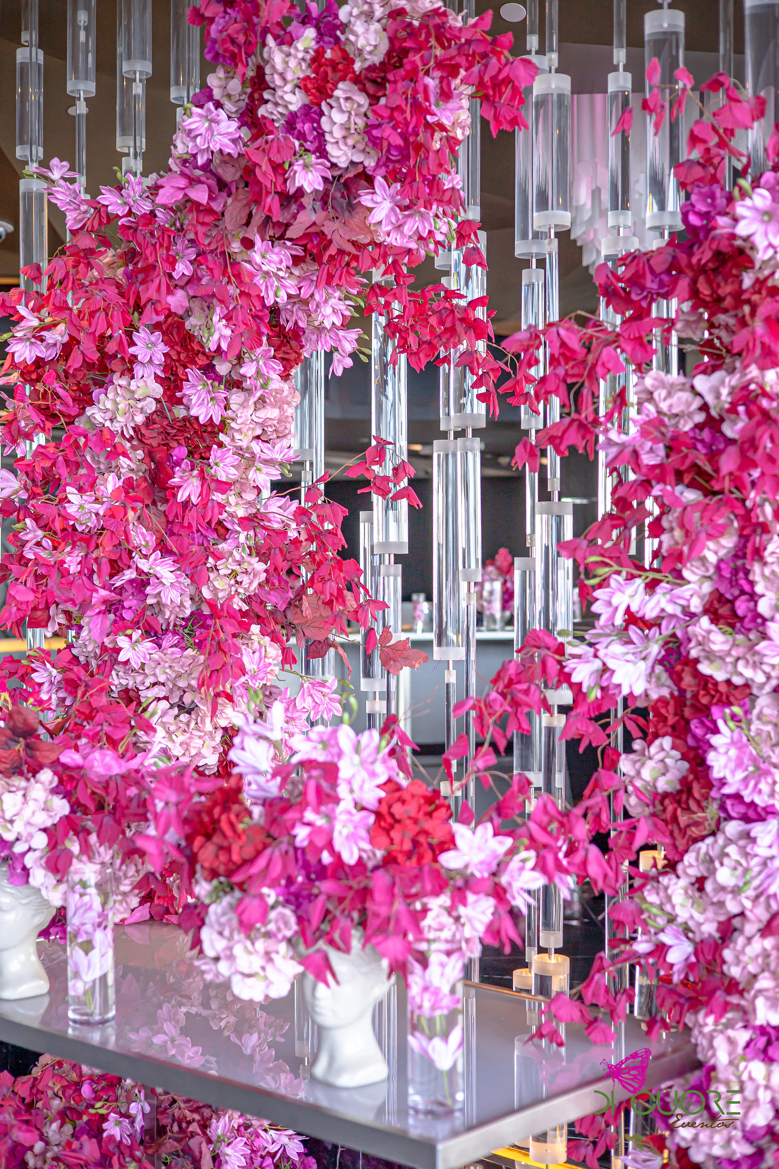 Cascade of pink and fuchsia flowers among crystal rods, above a mirrored console with white vases