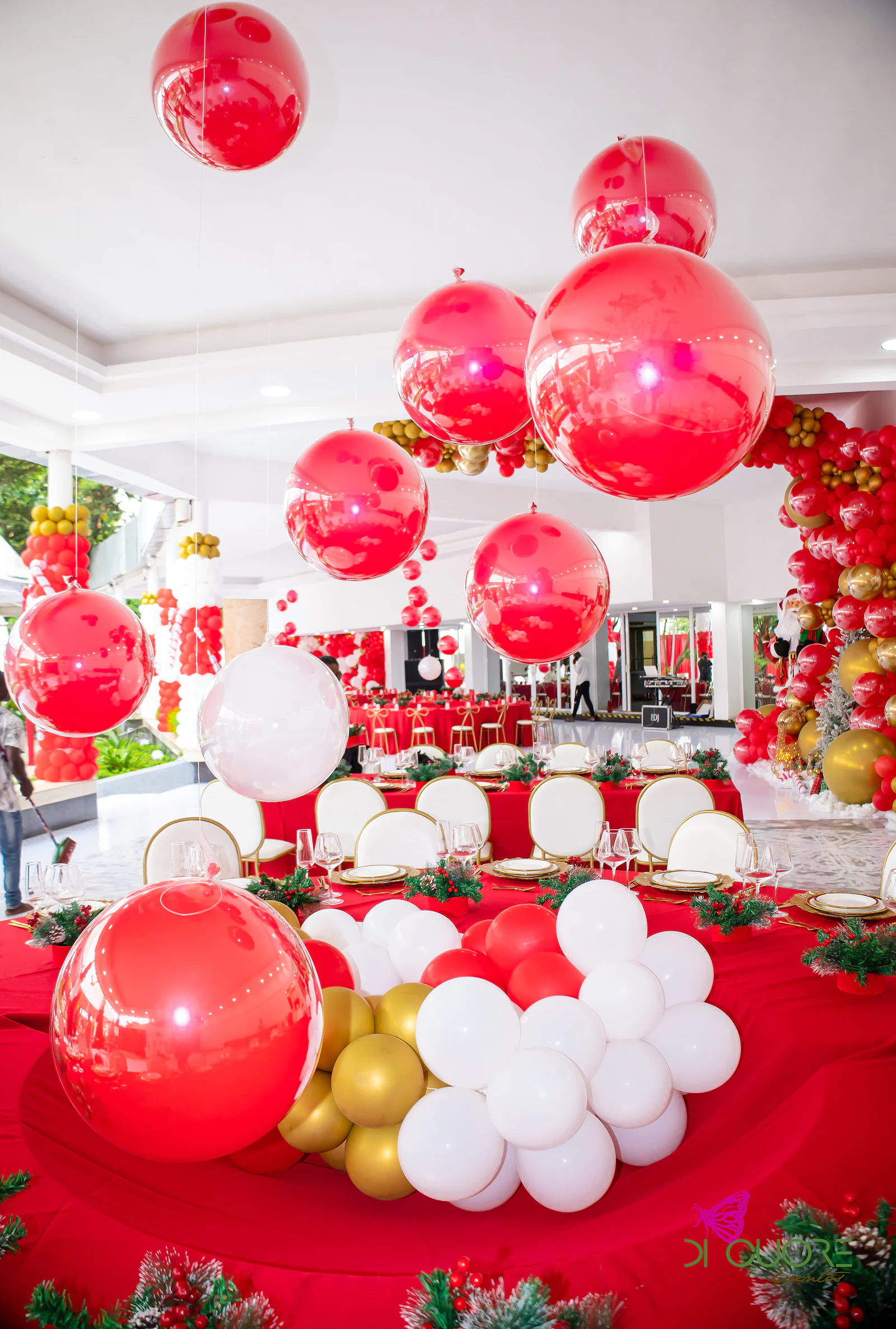 Mirrored red spheres hanging above a round table with a centrepiece of white, red and gold balloons