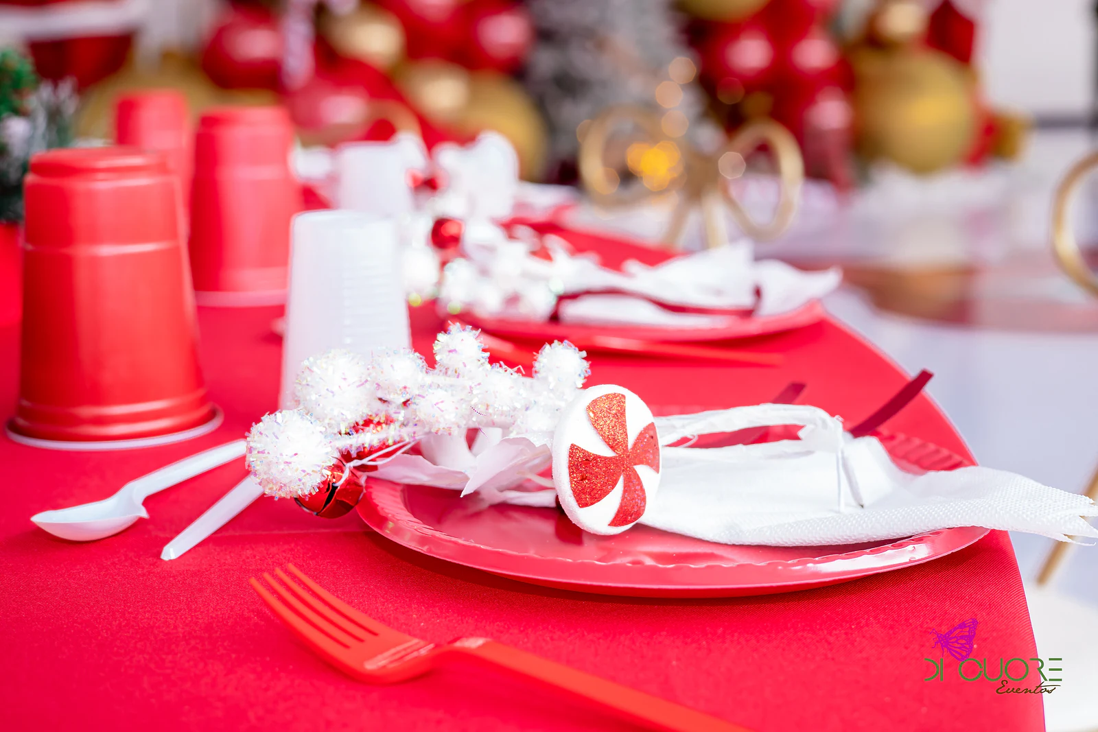 Children’s table with red cups and a red plate, a tied white napkin and a peppermint sweet